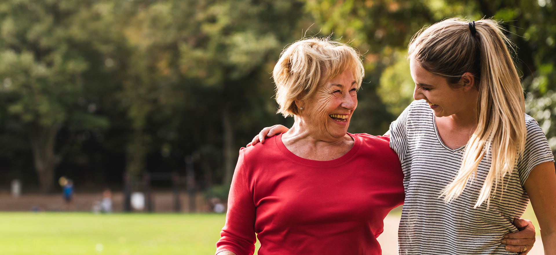 Mother and daughter laugh together in park
