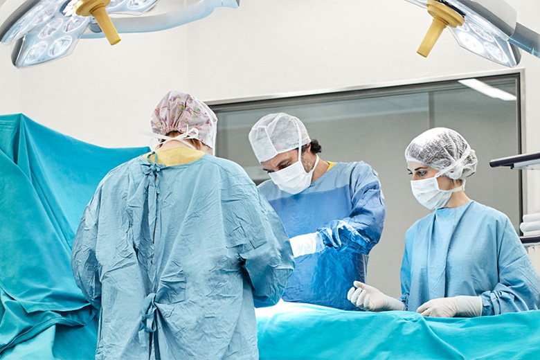 Surgeons and nurse perform surgery on patient